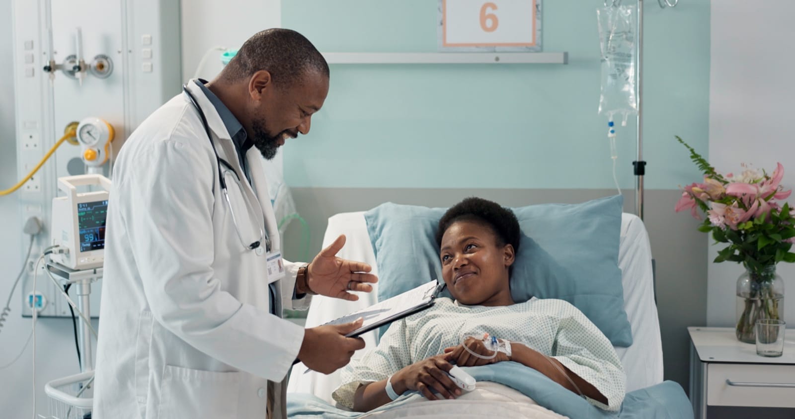 A doctor speaking with a patient recovering in a hospital bed