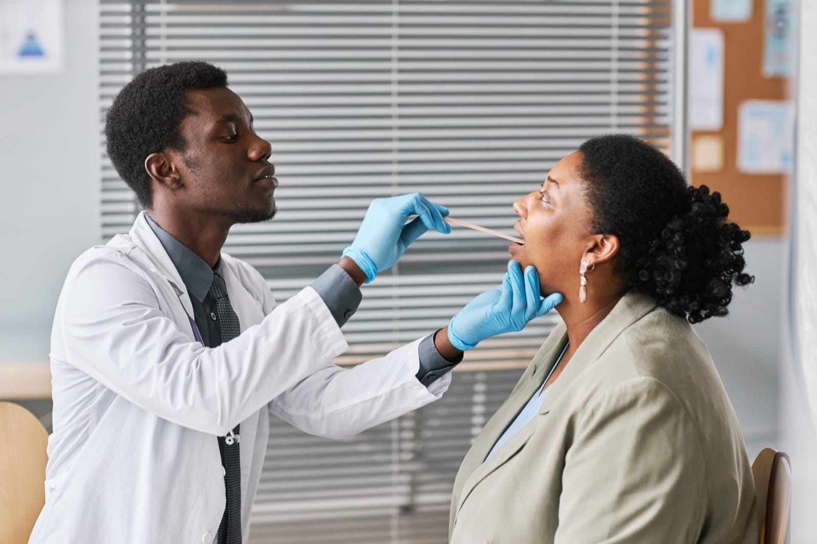 A clinician examining a patient’s throat